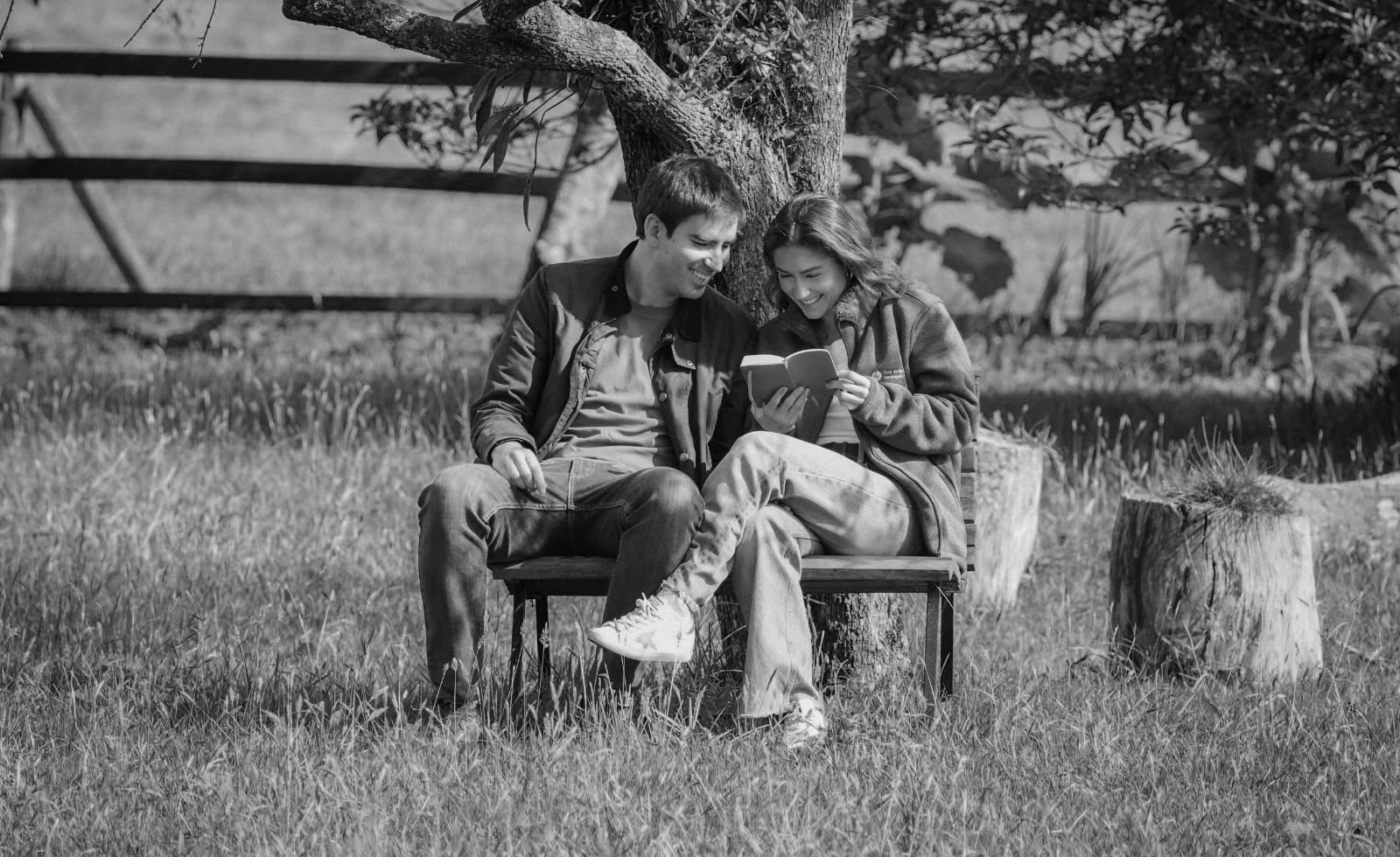 Paulina y Alberto leyendo en una banca bajo un árbol
